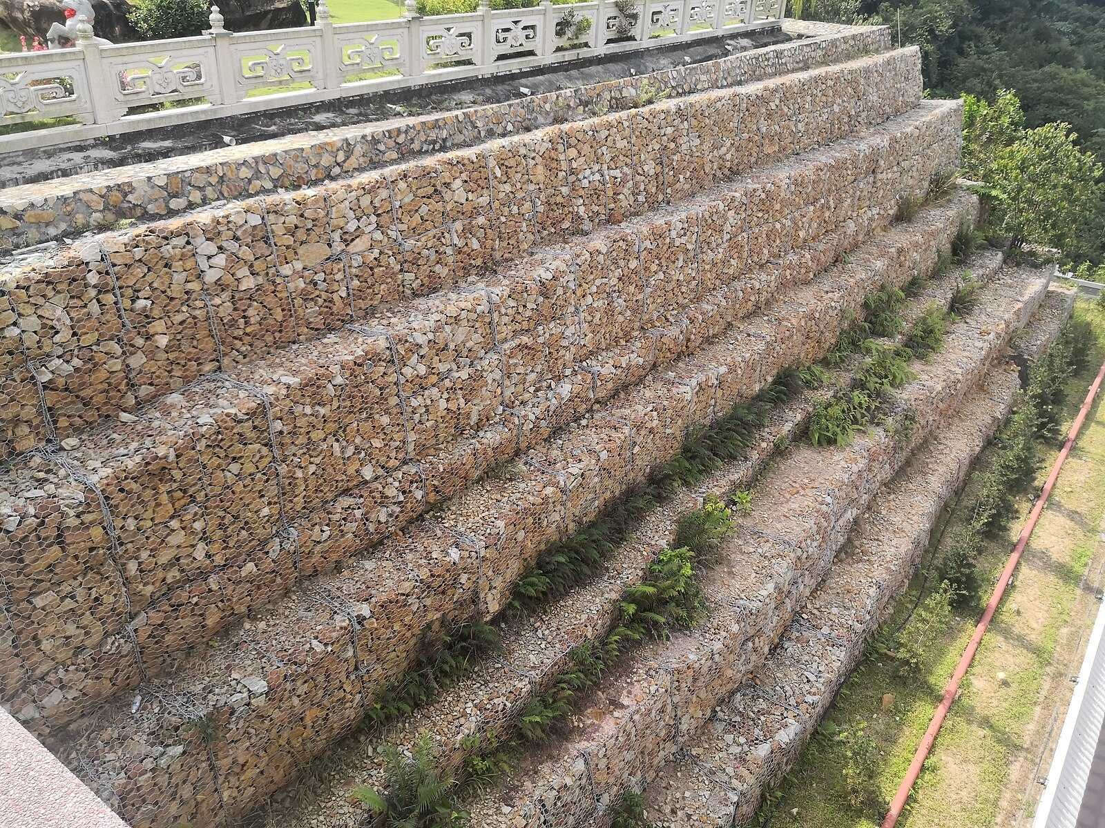 Terraced gabion rock retaining walls stepping down a steep slope