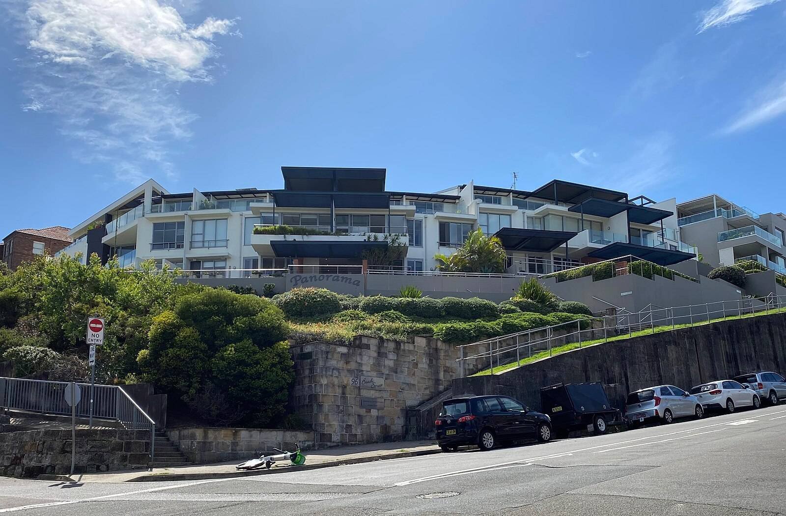 Tall sandstone retaining walls along a sloping residential street