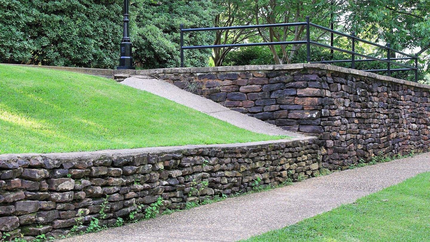 Stone retaining walls holding back a sloping lawn