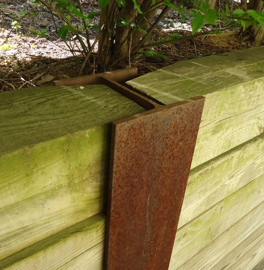 Steel post holding horizontal retaining wall sleepers in place